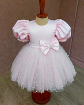 Front view of a pink puff sleeve pearl dress for girls, showcasing elegant pearl details and a voluminous tulle skirt.