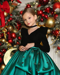 Close-up of pearl and satin accents on emerald green holiday dress for girls.
