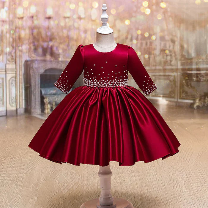 Front view of a red satin holiday dress for girls with pearl accents on the bodice, showcasing festive elegance and a classic silhouette.