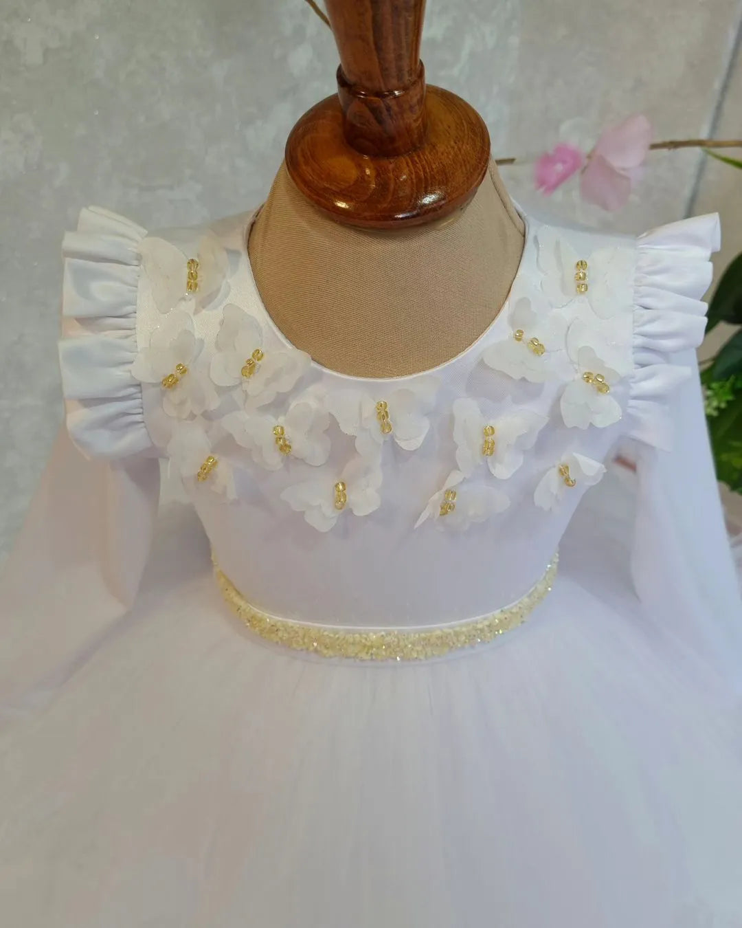 Close-up of butterfly and floral details on white luxury dress for girls.