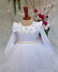 close view of white flower girl dress with butterfly accents and floral patterns.