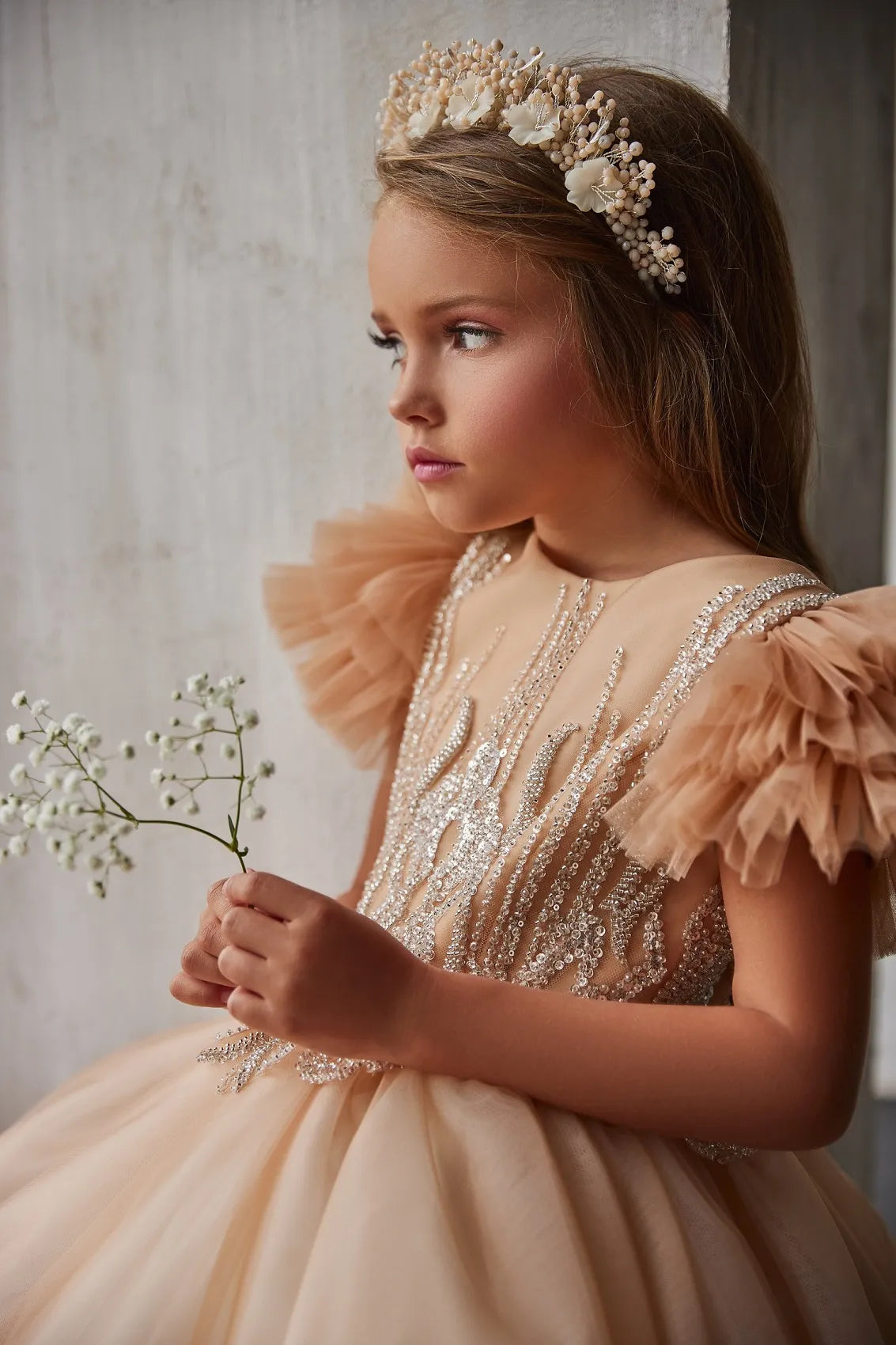 Detailed close-up of embellished lace bodice on champagne flower girl dress