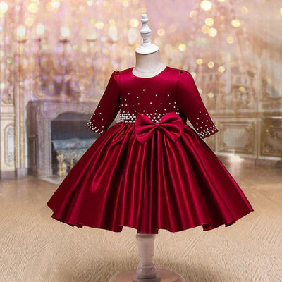 Side view of a red holiday dress for girls with a smooth satin finish and pearl detailing, highlighting the gown’s luxurious design.
